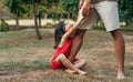 Cheerful smiling daughter with his father swinging on daddy`s leg outdoors. Ã¯Â¿Â½ute little girl playing with her loving dad in the Royalty Free Stock Photo